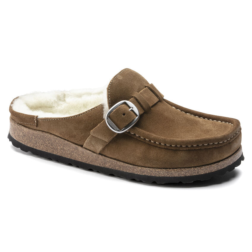 A brown suede Birkenstock moccasin-style clog with a shearling lining and a buckle strap.