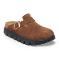 A brown suede Birkenstock clog featuring a single side strap with a metallic buckle, set on a thick black lug sole.