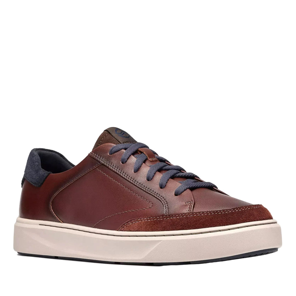A low-top leather sneaker in a rich reddish-brown color, featuring dark gray laces, a dark navy heel tab, and a thick cream-colored midsole.