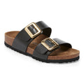 Black sandals with gold buckles on a white background