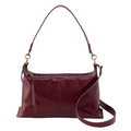 A leather shoulder hobo bag in a maroon color with brushed antique brass hardware and a suede and leather lining.